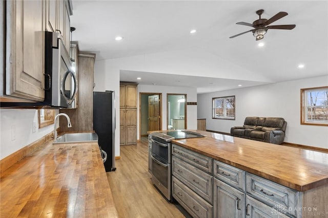 kitchen with light hardwood / wood-style flooring, vaulted ceiling, wooden counters, and appliances with stainless steel finishes