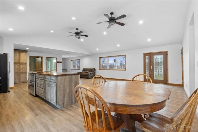 dining room with vaulted ceiling, ceiling fan, and light hardwood / wood-style floors