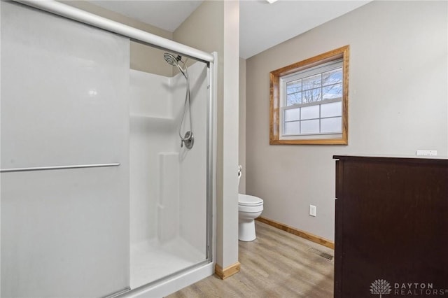 bathroom with wood-type flooring, a shower with door, and toilet