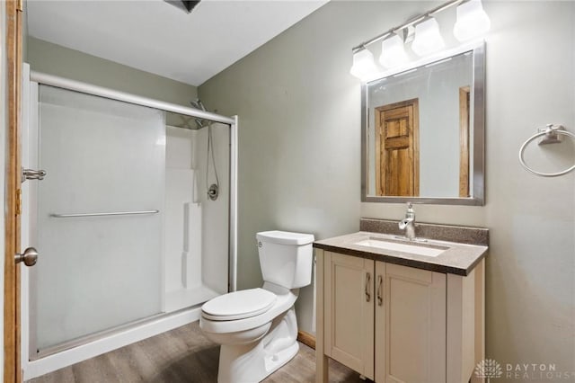 bathroom with hardwood / wood-style flooring, vanity, toilet, and a shower with door