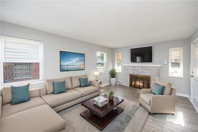 living room featuring a brick fireplace and light wood-type flooring