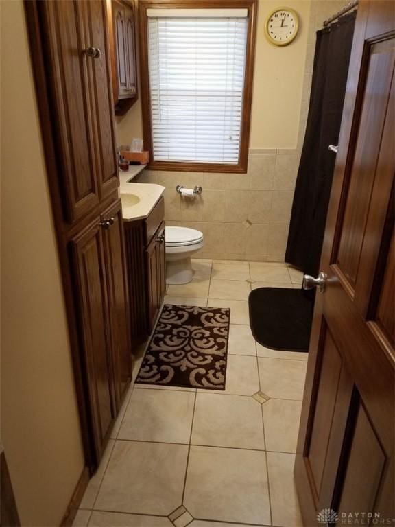 bathroom featuring tile walls, vanity, tile patterned floors, and toilet