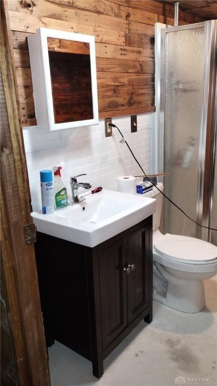 bathroom featuring vanity, toilet, wooden walls, and walk in shower