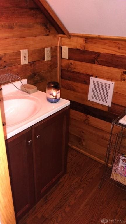 bathroom featuring vanity, hardwood / wood-style floors, and wooden walls