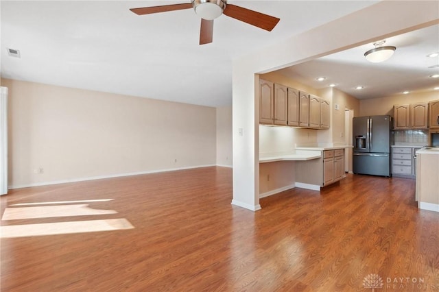 kitchen featuring dark hardwood / wood-style floors, built in desk, backsplash, ceiling fan, and stainless steel fridge with ice dispenser