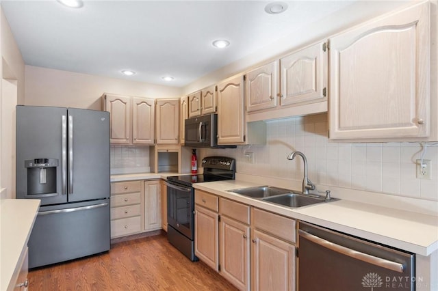 kitchen with sink, light hardwood / wood-style flooring, appliances with stainless steel finishes, backsplash, and light brown cabinets