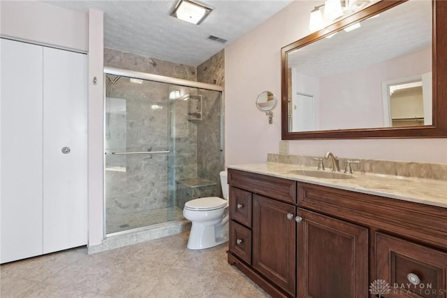 bathroom featuring vanity, a textured ceiling, toilet, and walk in shower