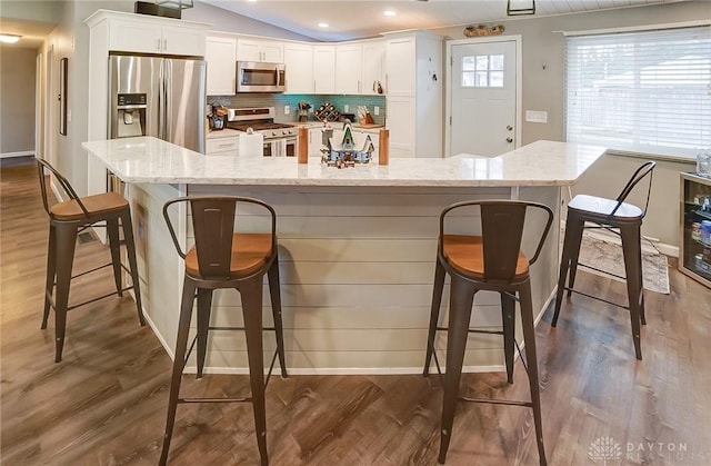 kitchen featuring light stone countertops, a breakfast bar, white cabinets, and appliances with stainless steel finishes