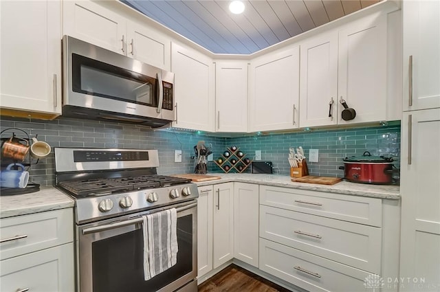 kitchen featuring stainless steel appliances, tasteful backsplash, light stone countertops, and white cabinets