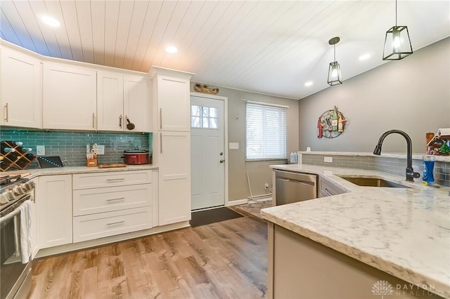 kitchen featuring appliances with stainless steel finishes, decorative light fixtures, sink, white cabinets, and light stone countertops