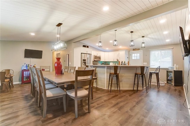 dining room with vaulted ceiling with beams, dark wood-type flooring, and wooden ceiling