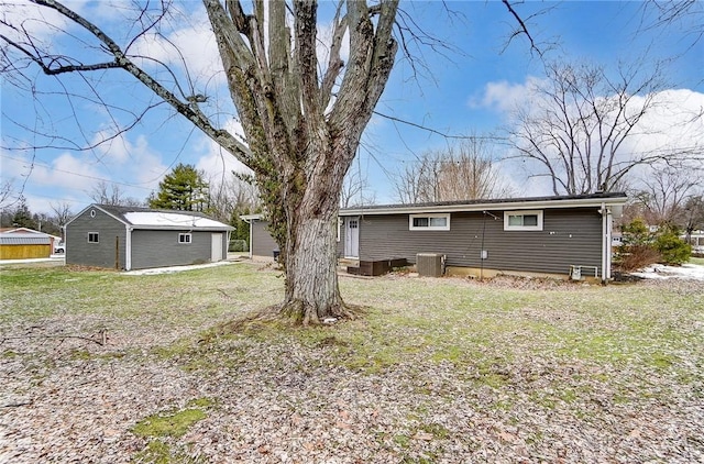 rear view of property with a yard, an outbuilding, and central air condition unit