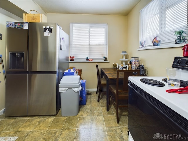 kitchen with stainless steel refrigerator with ice dispenser, plenty of natural light, and electric range oven