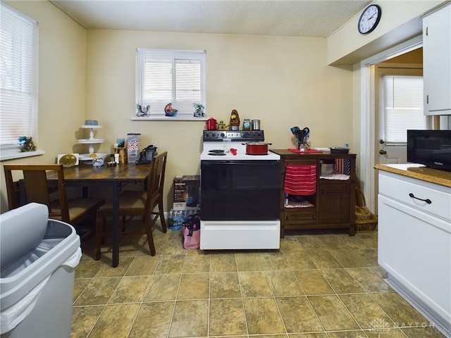 kitchen with electric range oven, white cabinets, and a textured ceiling