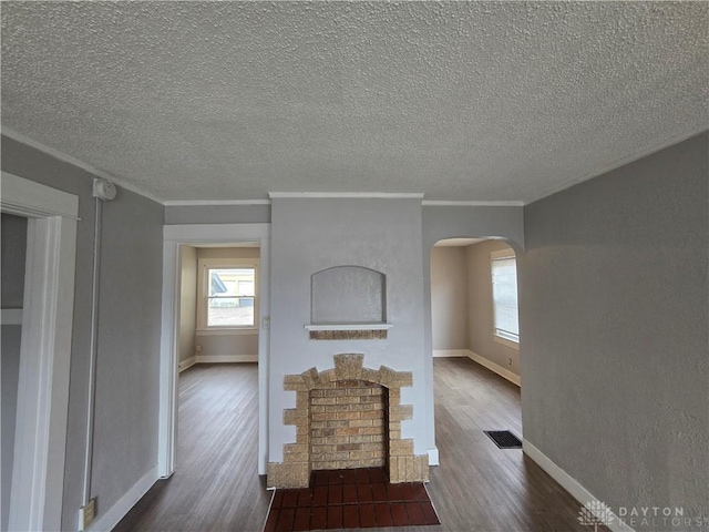 unfurnished living room featuring ornamental molding, dark hardwood / wood-style floors, and a textured ceiling