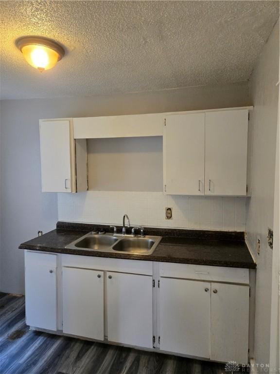 kitchen featuring dark hardwood / wood-style floors, white cabinetry, sink, decorative backsplash, and a textured ceiling