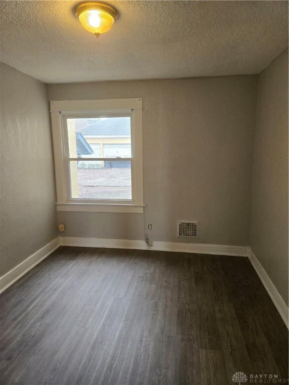 spare room featuring dark wood-type flooring and a textured ceiling