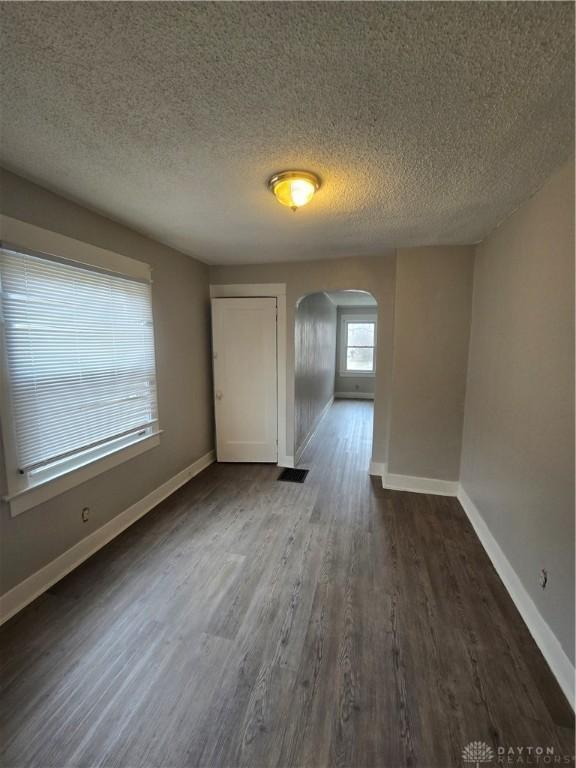 unfurnished room with dark wood-type flooring and a textured ceiling