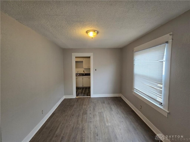 unfurnished room with dark wood-type flooring, sink, and a textured ceiling