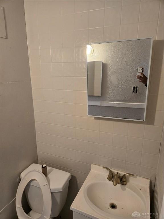 bathroom featuring vanity, tile walls, and toilet