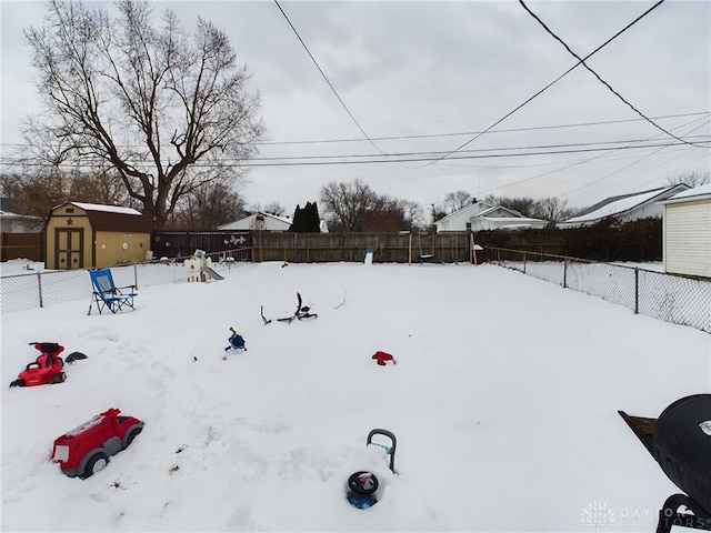 snowy yard featuring a storage shed