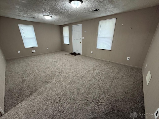 carpeted empty room featuring a textured ceiling