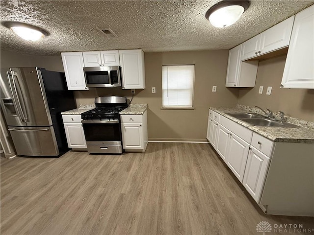 kitchen featuring sink, light hardwood / wood-style flooring, stainless steel appliances, and white cabinets