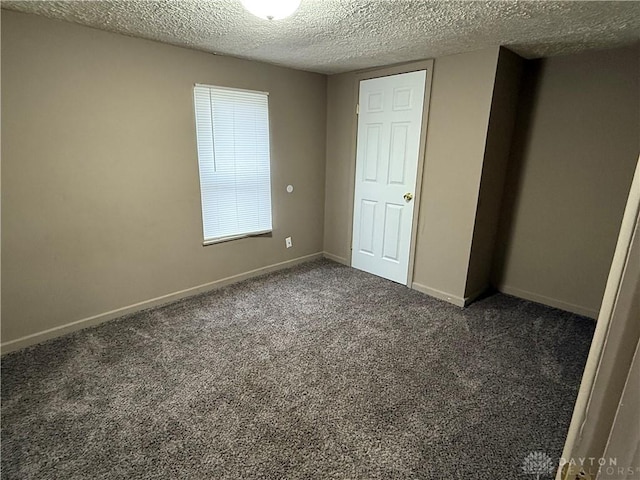 unfurnished bedroom with dark carpet and a textured ceiling