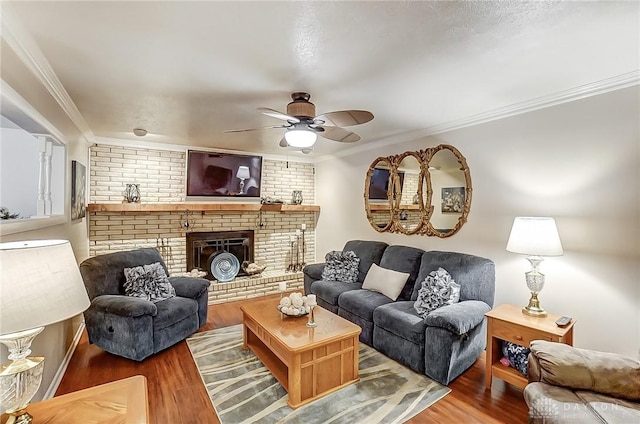 living room featuring hardwood / wood-style floors, crown molding, a brick fireplace, and ceiling fan