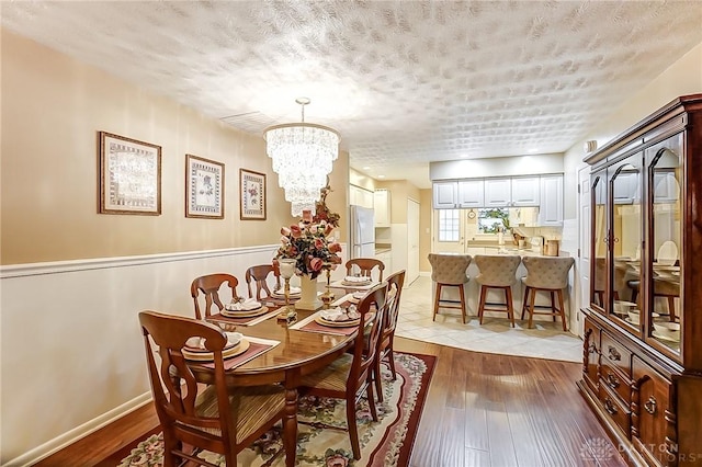 dining room featuring hardwood / wood-style floors, a textured ceiling, and a notable chandelier