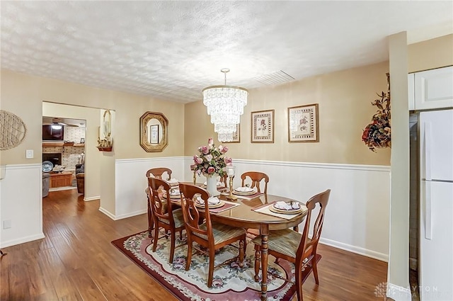 dining space with a notable chandelier, hardwood / wood-style flooring, and a textured ceiling