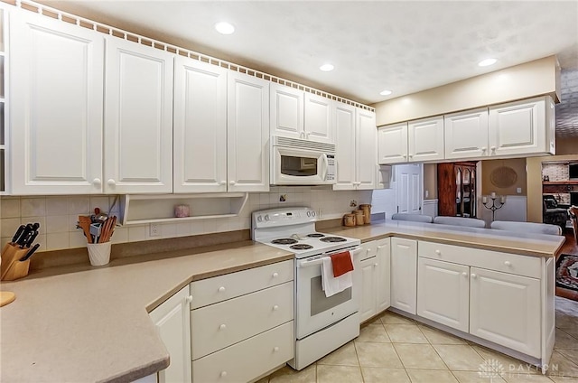 kitchen with white cabinetry, decorative backsplash, white appliances, and kitchen peninsula