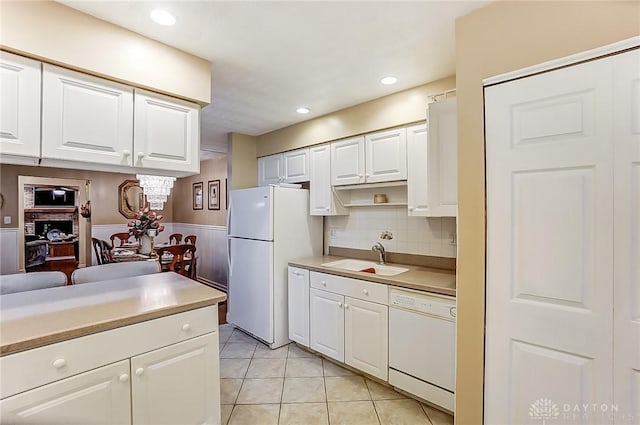 kitchen with sink, white appliances, light tile patterned floors, white cabinetry, and backsplash