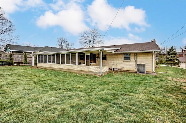 back of property with a sunroom, a yard, and central AC unit