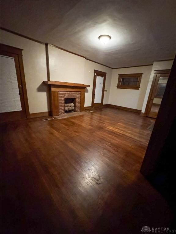 unfurnished living room featuring ornamental molding, a brick fireplace, and hardwood / wood-style floors