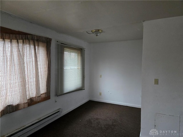 carpeted empty room with a baseboard heating unit