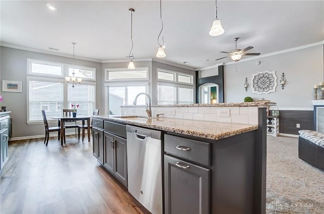 kitchen with sink, crown molding, dishwasher, light stone counters, and an island with sink