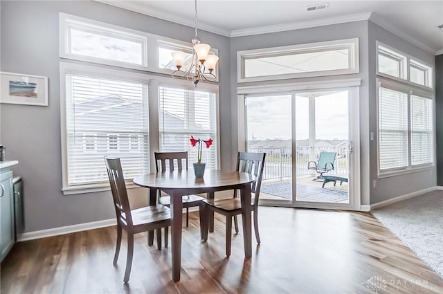 dining room featuring crown molding, a healthy amount of sunlight, wood-type flooring, and a notable chandelier