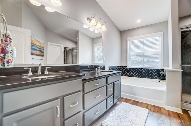 bathroom with vanity, vaulted ceiling, shower with separate bathtub, and hardwood / wood-style floors