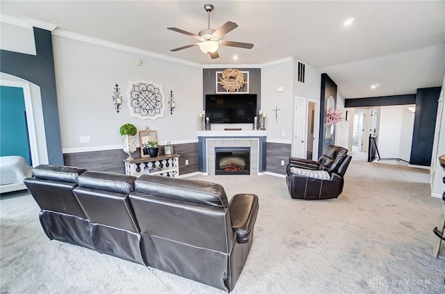 living room featuring crown molding, ceiling fan, carpet flooring, and a tiled fireplace