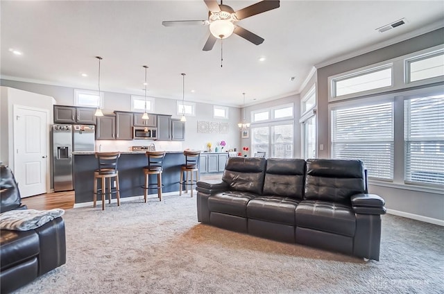 carpeted living room with crown molding and ceiling fan