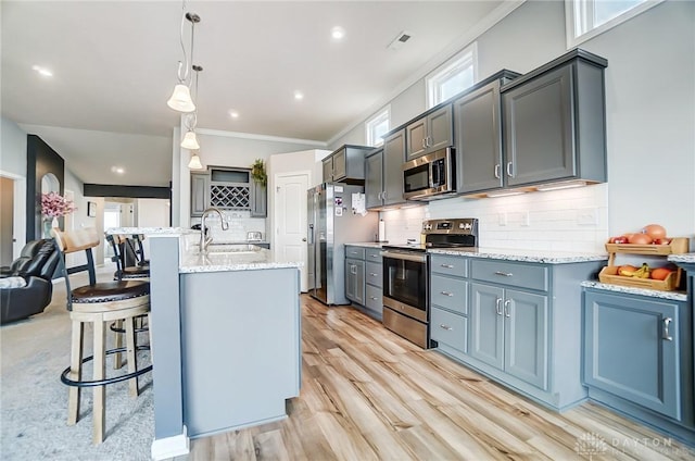 kitchen with pendant lighting, sink, light hardwood / wood-style flooring, backsplash, and stainless steel appliances