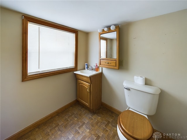 bathroom with vanity, parquet floors, and toilet