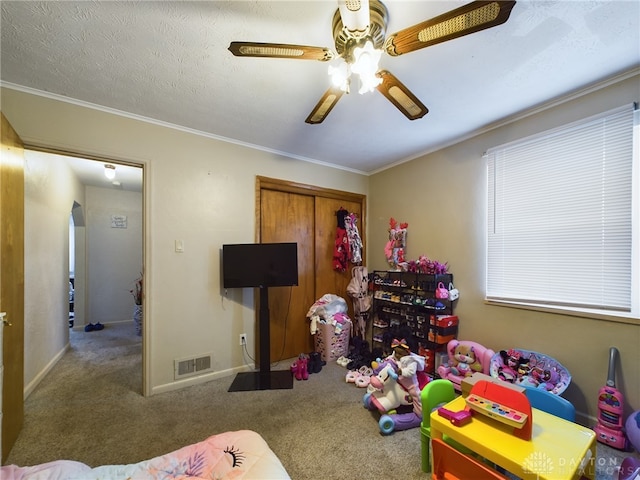 game room featuring ceiling fan, crown molding, a textured ceiling, and carpet