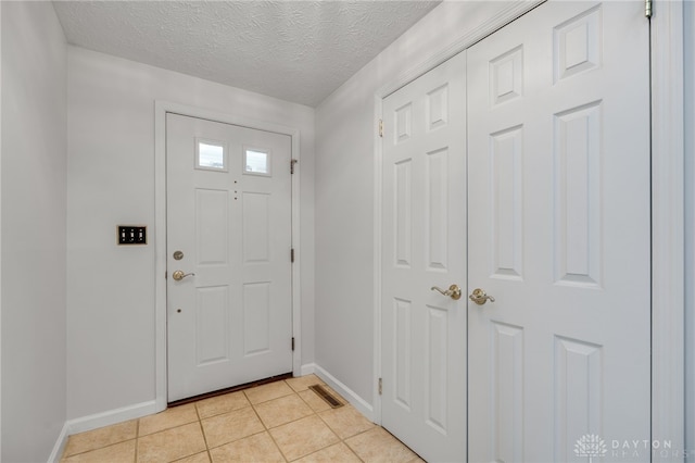 entryway featuring light tile patterned floors and a textured ceiling