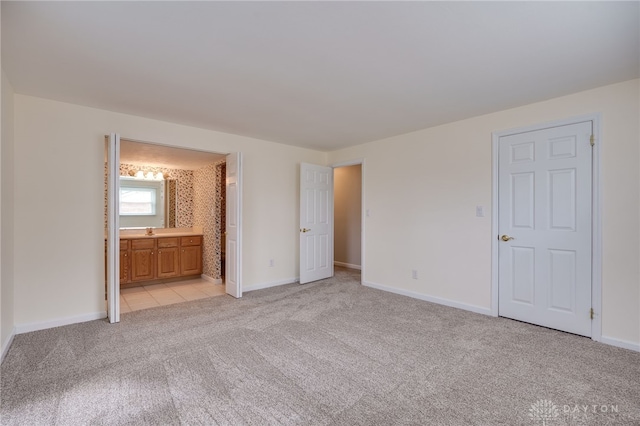 unfurnished bedroom featuring light carpet and ensuite bath