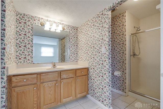 bathroom featuring tile patterned flooring, vanity, a shower with shower door, and a textured ceiling