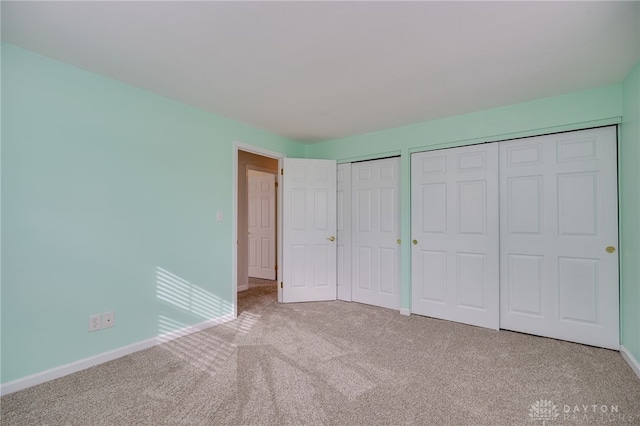 unfurnished bedroom with carpet flooring and two closets