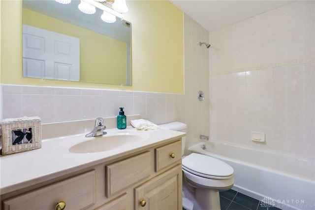 full bathroom with tile walls, vanity, tile patterned floors, toilet, and tiled shower / bath