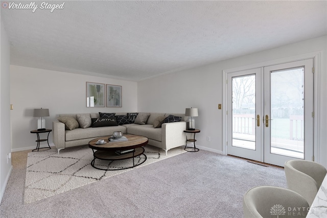 carpeted living room with french doors and a textured ceiling